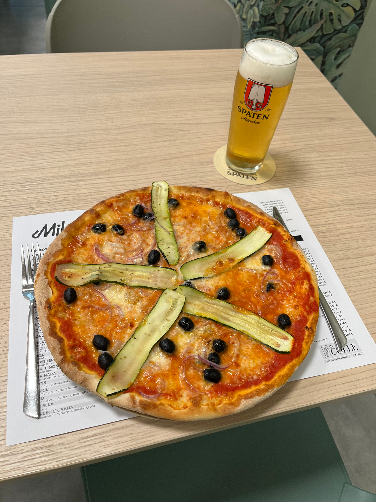 Pizza vegetariana MikyS con zucchine grigliate, cipolla rossa e olive nere, servita con una birra alla spina